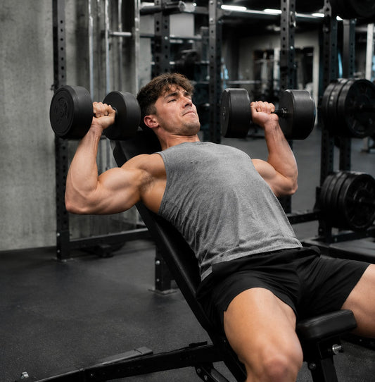 Natural lifter pushing through a difficult controlled dumbbell press set in a commercial gym